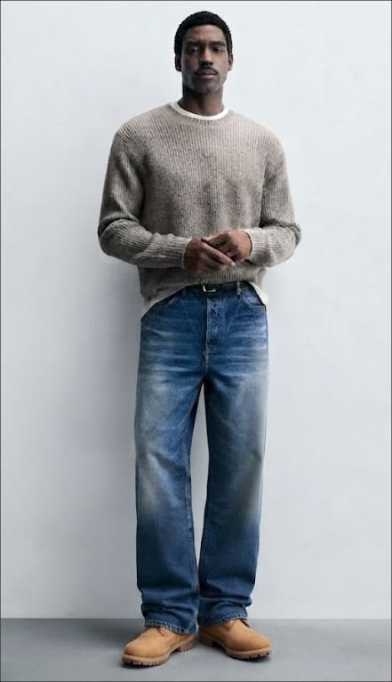 A young man wearing Straight-Leg Jeans, Crewneck Sweater, and Boots