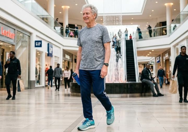 An older man wearing a running shoe in the mall