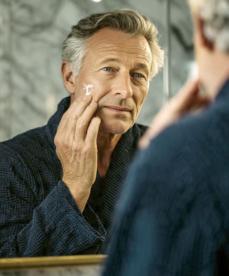 An older man performing skincare depicting older men's body grooming