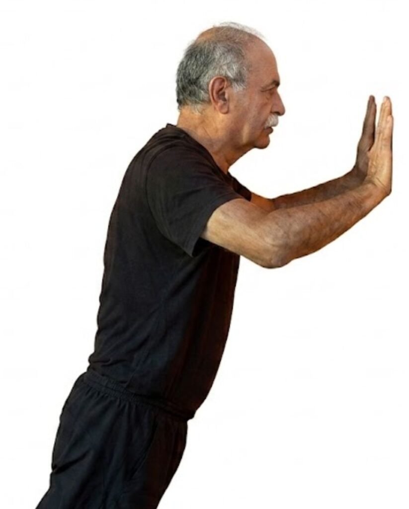 A man in his 60s doing wall push-up exercise 