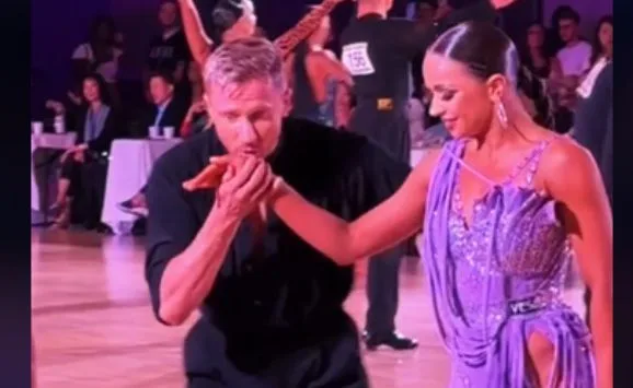 A man kissing a woman's hand after dancing as a mark of courtesy