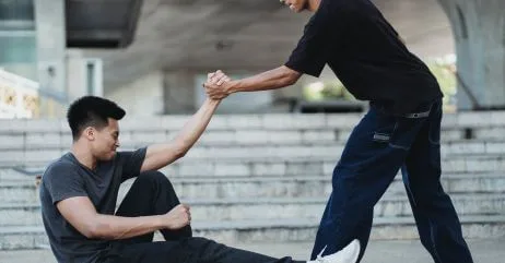 A man helping a man up in a demonstration of chivalry