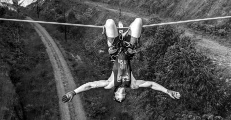A man hanging by a rope over a road